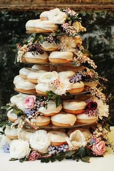 a tower of donuts decorated with flowers and greenery