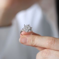 a close up of a person's hand holding a ring with a flower on it