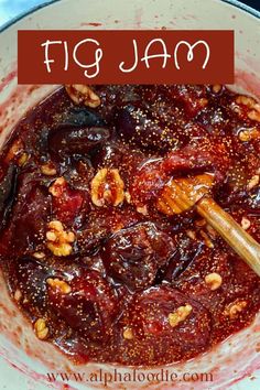 a bowl filled with meat and nuts on top of a table next to a wooden spoon