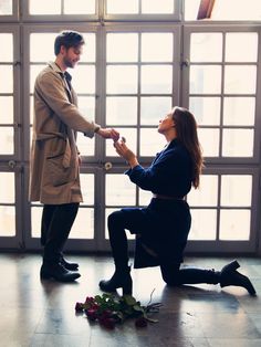 a man kneeling down next to a woman in front of a door with flowers on the floor