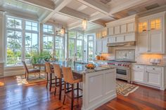 a large kitchen with white cabinets and wooden flooring, along with an island in the middle