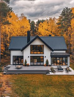 a white house surrounded by trees with yellow leaves