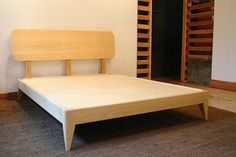 a wooden bed frame sitting on top of a carpeted floor next to a white wall