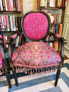 a pink chair sitting in front of a bookshelf filled with lots of books