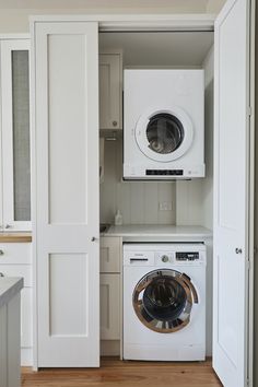 a washer and dryer in a small room with white cabinets on the wall