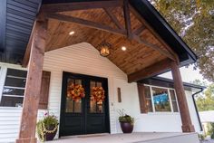 the front porch is decorated with wreaths and fall decorations on the door, along with potted plants