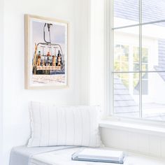 a white bench sitting in front of a window next to a wall with pictures on it