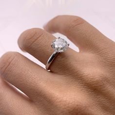 a woman's hand with a diamond ring on her left hand, showing the center stone