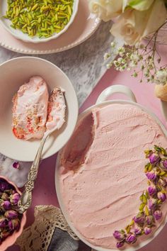 pink frosted cake with sprinkles and flowers in bowls on the table