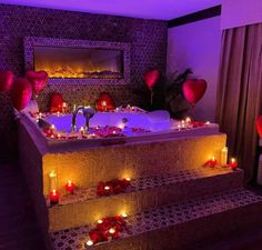 candles are lit on the steps leading up to a jacuzzi tub filled with hearts