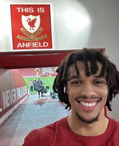 a man with dreadlocks standing in front of anfield