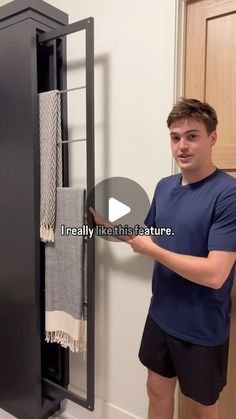 a young man is standing in front of a black cabinet with towels hanging on it