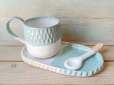 a cup and saucer sitting on top of a wooden table next to a spoon