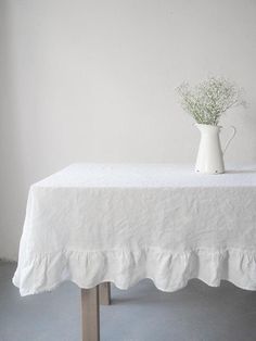 a white vase sitting on top of a table next to a plant in the middle