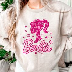 a woman wearing a sweatshirt with the word barbie on it and stars around her neck