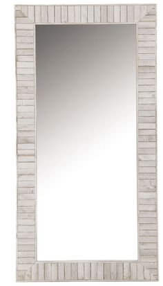 a white wooden frame mirror sitting on top of a table