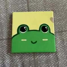 a green frog with big eyes sitting on top of a bed