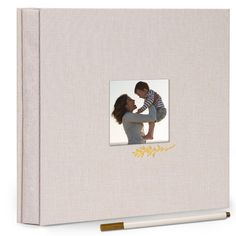 a photo album with a white cover and gold lettering on the front, featuring an image of a woman holding a baby