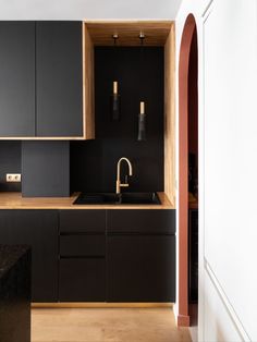 a kitchen with black cabinets and wooden counter tops, along with a sink that has gold faucets on it