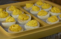 an egg tray filled with deviled eggs on top of a wooden table