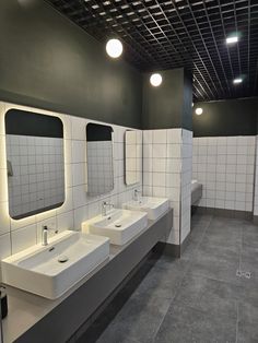 a public restroom with three sinks and two urinals