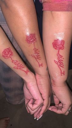 two people holding hands with tattoos on their arms and the words family written in red ink