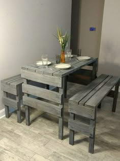 a table and bench made out of wooden pallets with plates on the top one