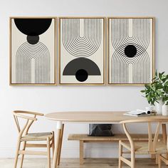 two black and white paintings hanging on the wall above a dining room table with chairs