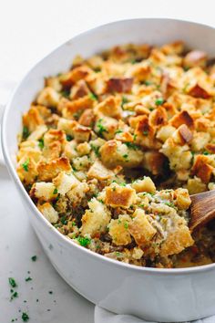 a casserole dish filled with stuffing and topped with a wooden serving spatula