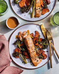 two plates with salmon, asparagus and broccoli covered in sauces