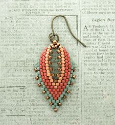 a pair of beaded earrings sitting on top of a piece of paper next to a book