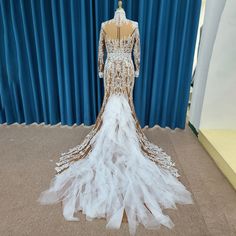 a wedding dress on display in front of a blue curtain