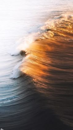 an ocean wave with the sun shining on it