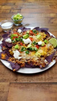 a white plate topped with nachos on top of a wooden table