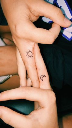 two people with matching tattoos on their fingers are holding each other's hands together