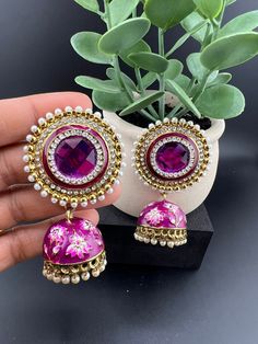 This a stunner Jhumka with Big size Stud in Purple and Gold, with pearls, CZ and Minakari work, Jhumka earrings. It is a statement earring with shining big stone at the stud part and Minakari jhumki at the bottom. You cannot miss the gorgeous look of it. This earring is a statement piece and a perfect one for Indian weddings.  Color : Purple, Gold and Pearl length : 3 inch width : 1.75 inch Each earring Weight : 32.9 grams Material : Brass , Stone, Pearls, beads, CZ Beautiful Viral High Quality, Heavy Multicolor Jhumkas For Celebration, Purple Earrings Indian, Heavy Pink Jhumkas For Celebration, Purple Jhumka Earrings, Traditional Pink Cutdana Jhumkas, Dark Magenta, Purple Pearl, Indian Earrings, Purple Earrings