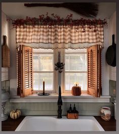 the kitchen window is decorated with pumpkins and gingham checkered valances