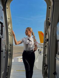 a woman in uniform is walking out of an airplane door with her hand up to the side