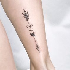 a woman's foot with an arrow tattoo on the left side of her leg