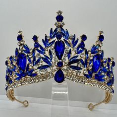 Experience the majestic shine of the Teklemon Tiara Crystal Crown, an exclusive queen tiara in precious gold, decorated with stunning sapphire blue rhinestones. This exquisite crown exudes royal elegance and adds a special, incomparable splendor to any occasion. The detailed craftsmanship and sparkling gemstones make this tiara a distinctive piece of jewelry. Perfect for weddings, galas or as a special accessory, this standard-sized tiara ensures a comfortable and secure fit and lets you shine i Blue Crown, Crystal Crown, Crystal Tiaras, Fancy Jewellery, Rhinestone Designs