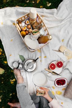 a person sitting on a blanket with food and drinks