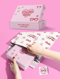 a pink box with hearts on it and a woman's hand opening the lid