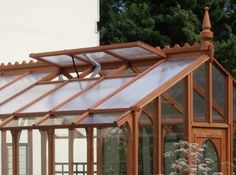 a wooden greenhouse with glass walls and roof