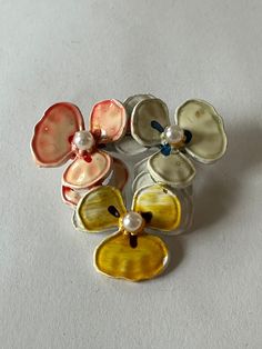 Introducing this exquisite midcentury metal brooch, a true treasure for any vintage jewelry lover. Inspired by nature's beauty, this brooch showcases three pansy flowers in peach, white, and yellow blooms, each adorned with delicate faux pearl centers. The attention to detail is simply mesmerizing, capturing the essence of retro elegance. This brooch is not only a stunning accessory but also a timeless piece oozing with sentimental value. It makes a perfect anniversary gift or a thoughtful birth Cheap Retro Flower Brooch, Vintage Gold Flower Brooch, Wedding Flower-shaped Enamel Brooches, Vintage Yellow Gold Flower Brooches, Pansy Flowers, Vintage Enamel Flower Brooch, Metal Brooch, Pansy Flower, Unique Brooch