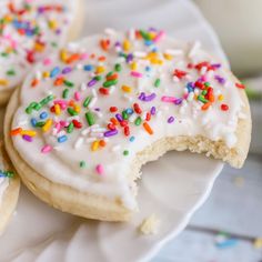 there are several decorated cookies on the plate with sprinkles next to a glass of milk