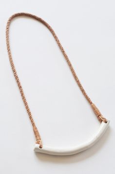 a white and gold necklace with a long chain hanging from it's center, on a white surface