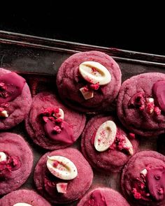 red velvet cookies with white chocolate chips and pink icing on top, sitting in a baking pan