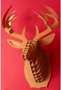 a paper sculpture of a deer's head on a red background, with the antlers visible