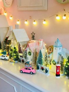 a christmas scene with toy cars, houses and trees on a mantle or mantel