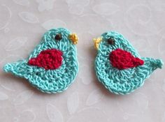 two crocheted birds sitting on top of a table